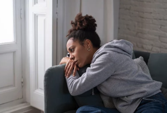 Black woman reflecting on a couch